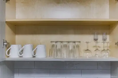a shelf with glasses and wine glasses on it at The Cozy Garden Suite - South Surrey Stay in White Rock