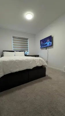 a bedroom with a bed and a tv on the wall at 3BR Family House in NE Edmonton in Edmonton