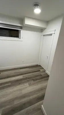 an empty room with white walls and wood floors at Cozy 2 bedroom suite in Edmonton