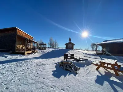 a snow covered ground with a building and a sun at The Wolf Cabin - Bear Creek Cabins in Winfield