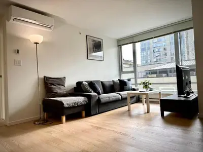 a living room with a black couch and a television at Pleasant and convenient 1B1B close to Richmond Center in Richmond