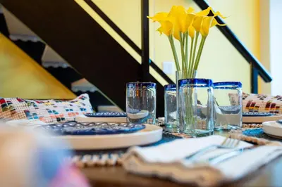 a table with a vase with yellow flowers in it at Casa DT Vancouver - Mexican Theme in Vancouver