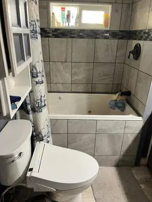 a bathroom with a white toilet and a bath tub at Rustic suite in small town Alberta Canada in Penhold