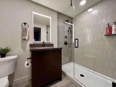 a bathroom with a shower and a sink and a toilet at New Condo with Pool and Hot Tub Sleeps 9 in Canmore