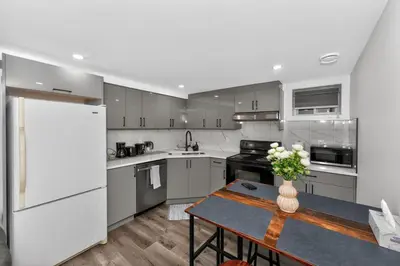 a kitchen with a table and a white refrigerator at New 2BR Home - Family Friendly - Near YYC Airport & Downtown - 4412 - DN in Calgary