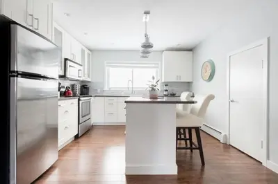 a kitchen with white cabinets and a stainless steel refrigerator at Spacious One Bedroom Queen Bed Inner City Stay in Calgary
