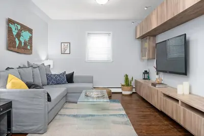 a living room with a gray couch and a flat screen tv at Spacious One Bedroom Queen Bed Inner City Stay in Calgary