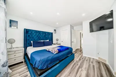 a bedroom with a blue bed and a flat screen tv at Cozy Vacation Home in Calgary