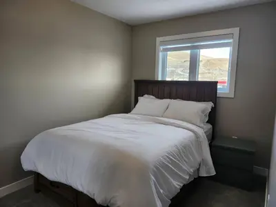 a bedroom with a large white bed with a window at Harmony Haven in Drumheller in Drumheller