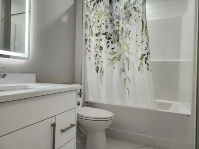 a white bathroom with a toilet and a shower curtain at Harmony Haven in Drumheller in Drumheller