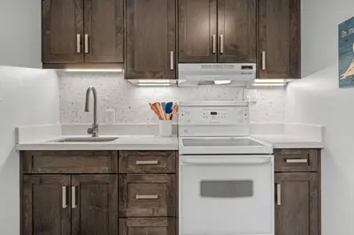 a kitchen with wooden cabinets and a white stove top oven at Mid Century Zen Suite. 1 BR. Near DT, C-train. in Calgary