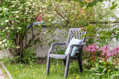 a chair sitting in the grass near some flowers at Funky 1 BR Century Home-Near DT, C-train in Calgary