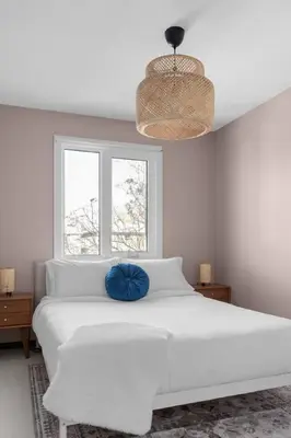 a white bedroom with a large white bed with a blue pillow at Bright and Welcoming Mount Pleasant Home, near DT in Calgary