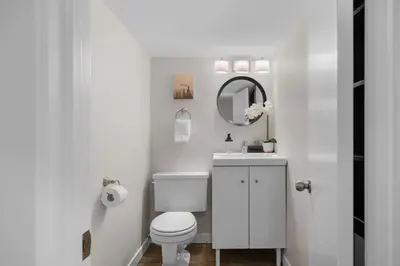 a white bathroom with a toilet and a mirror at Bright and Welcoming Mount Pleasant Home, near DT in Calgary