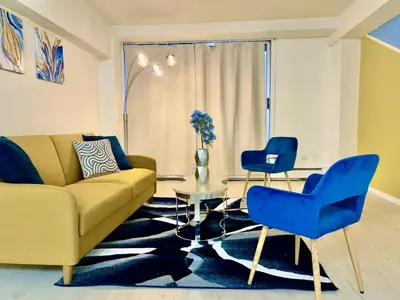a living room with a yellow couch and blue chairs at Cool and Cozy 17th Ave Nest in Calgary