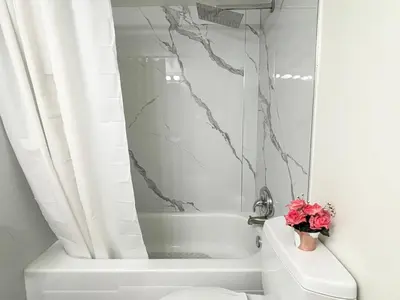 a bathroom with a white tub and a toilet at Cool and Cozy 17th Ave Nest in Calgary