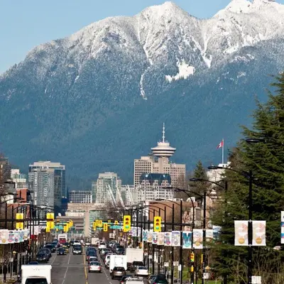 a busy city street with a mountain in the background at Modern 3-Bdrm Home & Parking - Cambie Village-VGH in Vancouver
