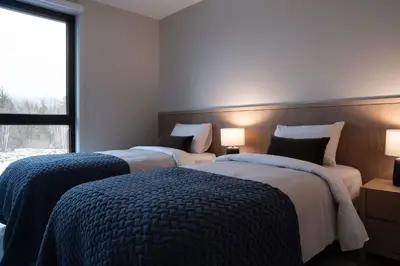 two beds in a hotel room with a window at Luna Ridge - Thoughtfully Designed 3-Bedroom Condo in Revelstoke