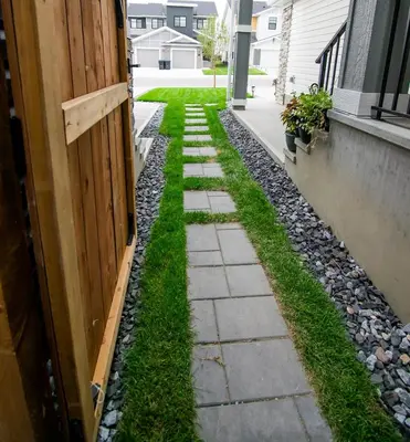 a backyard walkway with grass and rocks next to a door at Cozy Luxe 1BR Suite in Calgary