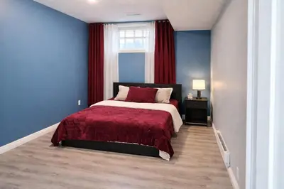a bedroom with a large bed with a red blanket at Home Basement, Friendly Family in Calgary
