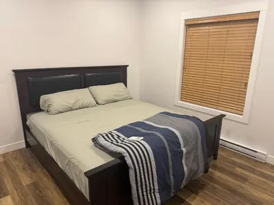 a bedroom with a bed and a window with a blanket on it at Next rental in Vernon