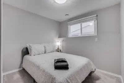 a white bedroom with a bed and a window at Edmonton House w/5BR/3BA/2Kitchens & Fenced Yard in Edmonton