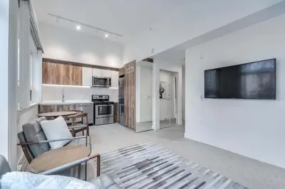 a living room with a tv and a kitchen at Modern Studio Condo in Central Prime Location in Vancouver