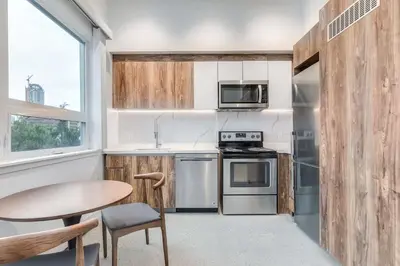 a kitchen with stainless steel appliances and a table at Modern Studio Condo in Central Prime Location in Vancouver