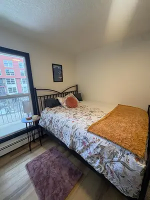 a bedroom with a bed and a large window at Charming Mission Downtown Condo in Calgary