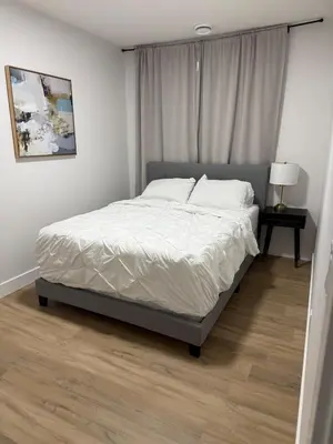 a bedroom with a bed with white sheets and pillows at Cozy 1 Bedroom suite close to west edmonton mall in Edmonton