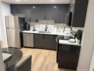 a kitchen with black and white cabinets and a table at Cozy 1 Bedroom suite close to west edmonton mall in Edmonton