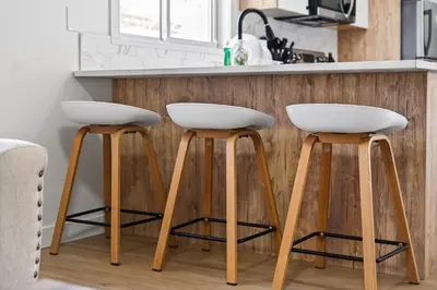 two white bar stools in front of a kitchen counter at Affordable & Cozy 3-bedroom, Minutes to City Core in Calgary