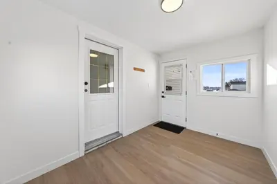 an empty living room with white walls and wood floors at Affordable & Cozy 3-bedroom, Minutes to City Core in Calgary