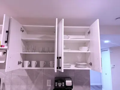 a white cabinet with plates and dishes in it at Cozy Haven 2 in Bélanger
