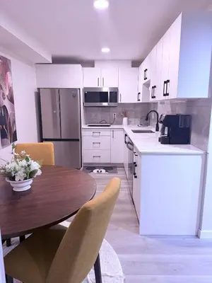 a kitchen with a wooden table and white cabinets at Cozy Haven 2 in Bélanger