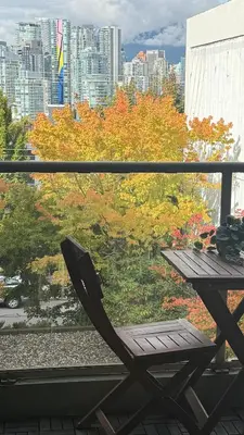 a table and chair on a balcony with a view of a city at City Line Views w Rooftop Patio in Vancouver