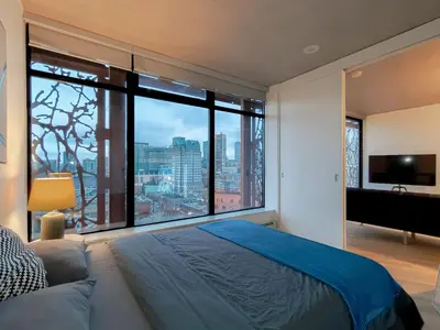 a bedroom with a bed and a large window at Gastown Unbeatable View 1 Bedroom High Floor Condo Rooftop View of Downtown in Vancouver