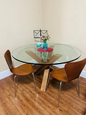 a glass table with two chairs and a vase with flowers at Moon rooms in Vancouver