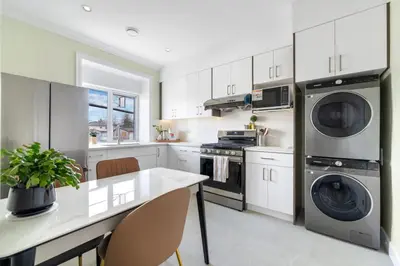 a kitchen with white cabinets and a table with a plant at Modern Vancouver Private Room-15 Mins to Downtown in Vancouver