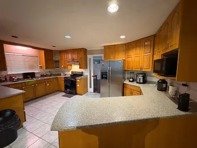 a kitchen with wooden cabinets and a stainless steel refrigerator at Surrey-Delta Urban Stay - Walk to Transit & Shopping in Surrey