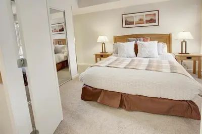 a bedroom with a large bed and a mirror at Heart of Whistler Village, Mountain Views, Pool & Hot Tub in Whistler