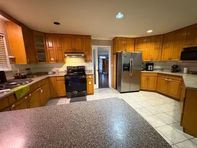 a kitchen with wooden cabinets and a stainless steel refrigerator at Nordel Way Guest House - Walk to Transit & Shopping - 20 Min to YVR in Surrey