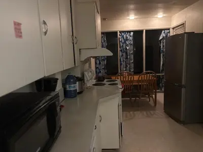 a kitchen with white cabinets and a refrigerator and a table at Vancouver Large Room for 5 - Near YVR Airport, Transit & Free Parking in Vancouver