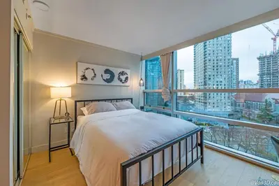 a bedroom with a bed and a large window at Beautiful Downtown Studio with Parking in Vancouver