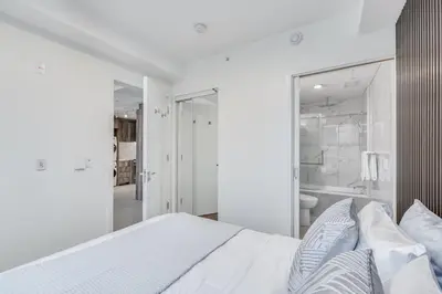 a white bedroom with a bed and a bathroom at Upscale 1BR2BA Walk Everywhere in Vancouver