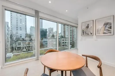 a dining room with a table and chairs and large windows at Upscale 1BR2BA Walk Everywhere in Vancouver