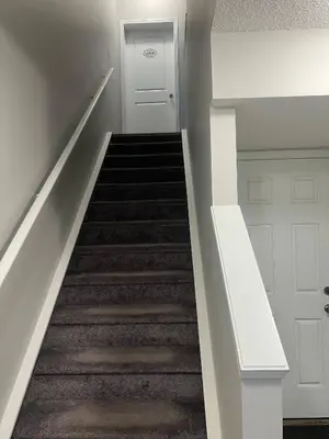 a hallway with a staircase with a white door at Spacious Private Room with TV, WiFi and Fridge in Edmonton