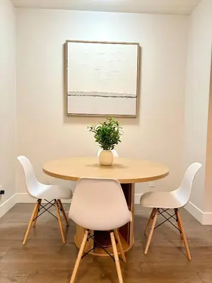 a dining room table with white chairs and a potted plant at Royal Bay Guest Suite in Victoria