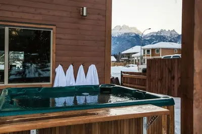 a jacuzzi tub on a porch with a view of mountains at Big Bear Chalet and spa in Revelstoke