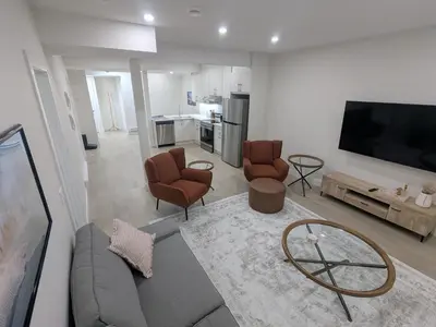 a living room with a couch and chairs and a tv at Greystone Retreat - Walk to River & Downtown in Cochrane